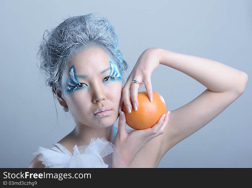 Portrait of woman with creative makeup and orange in her hands. Portrait of woman with creative makeup and orange in her hands