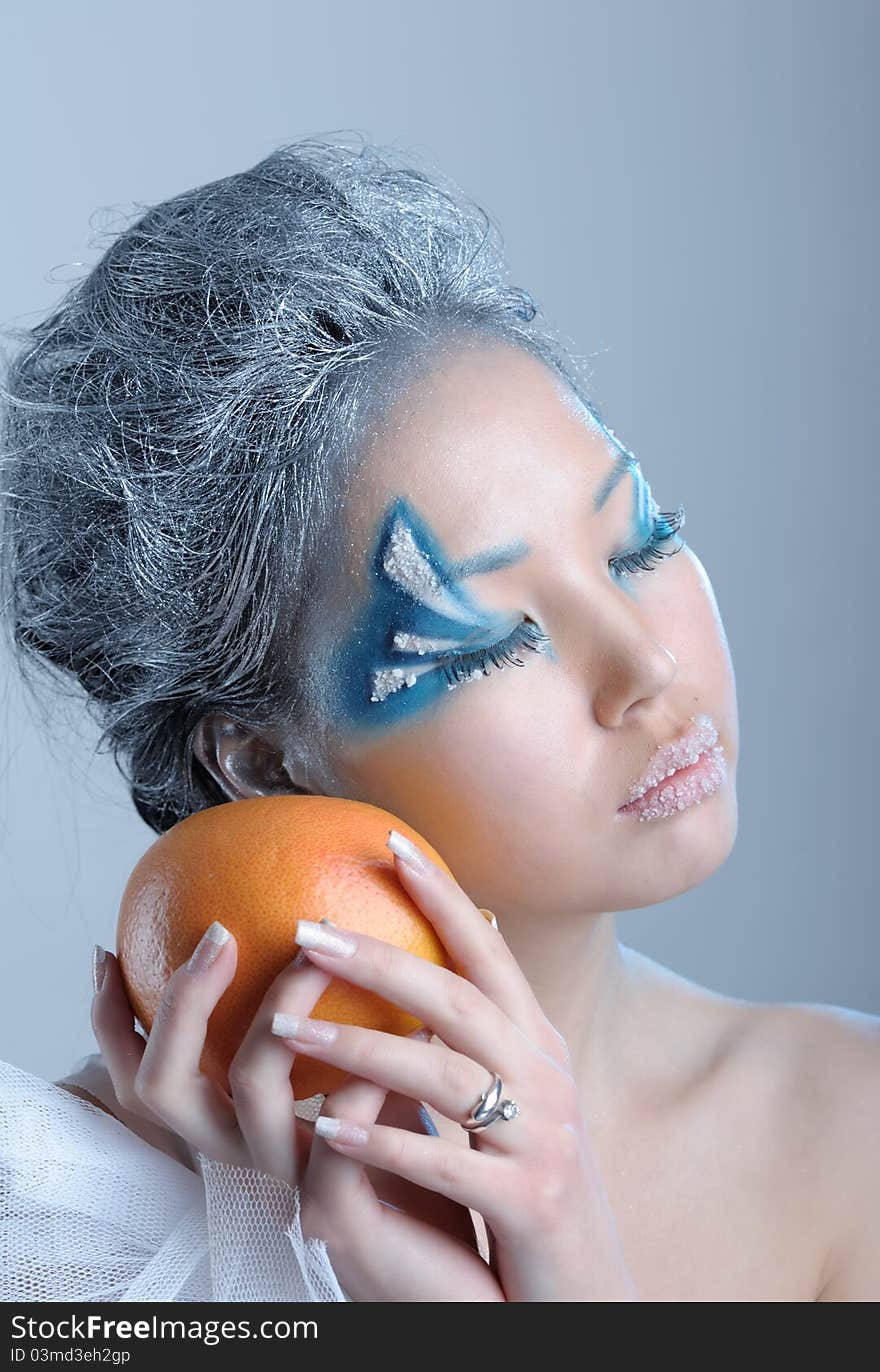 Portrait of woman with creative makeup and orange in her hands. Portrait of woman with creative makeup and orange in her hands