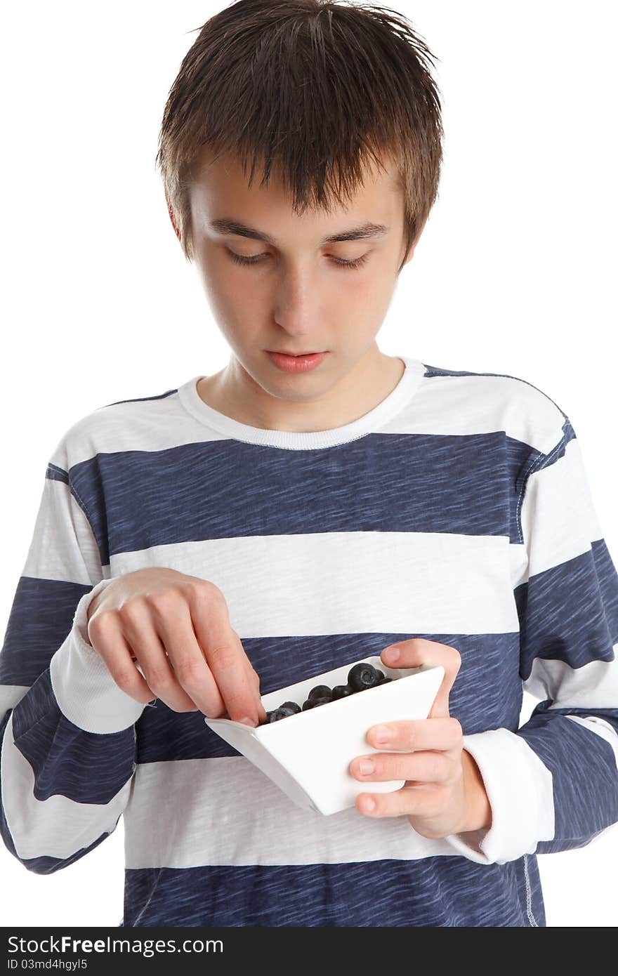 A child eats fresh blueberries from a small white bowl. A child eats fresh blueberries from a small white bowl.