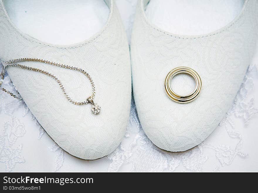 Engagement rings lie on the bride's shoes. Engagement rings lie on the bride's shoes