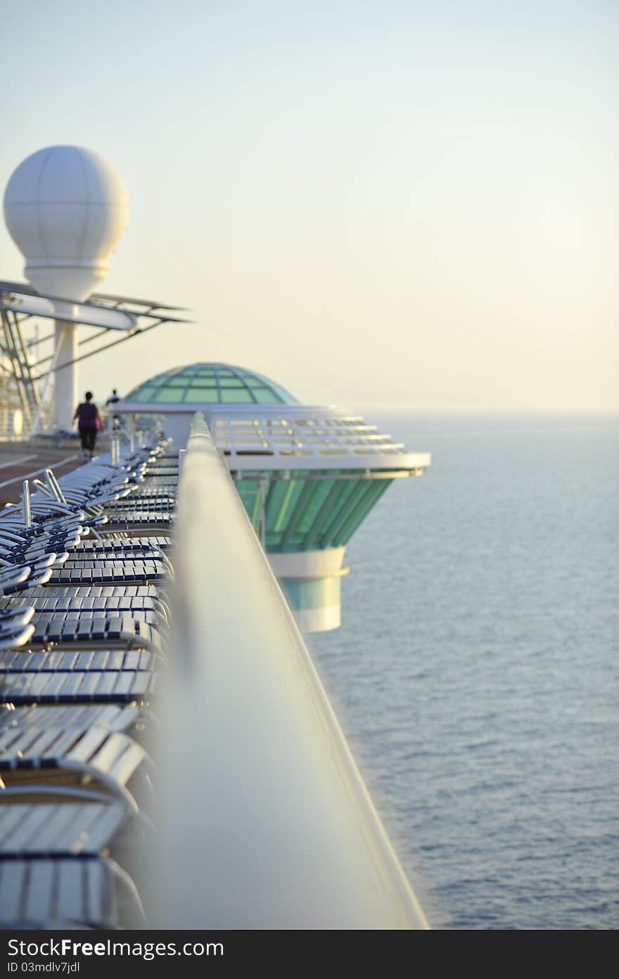 A View of  the rail on a ship in the morning sun picturing the row of deck chairs. A View of  the rail on a ship in the morning sun picturing the row of deck chairs