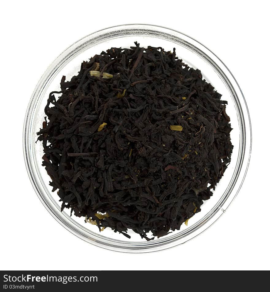 Black tea leaves in a glass bowl on white