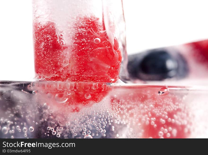 Raspberry and blackberry frozen in ice sticks on white