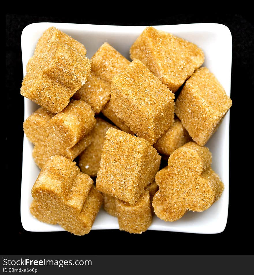 Brown sugar in a white bowl on black background