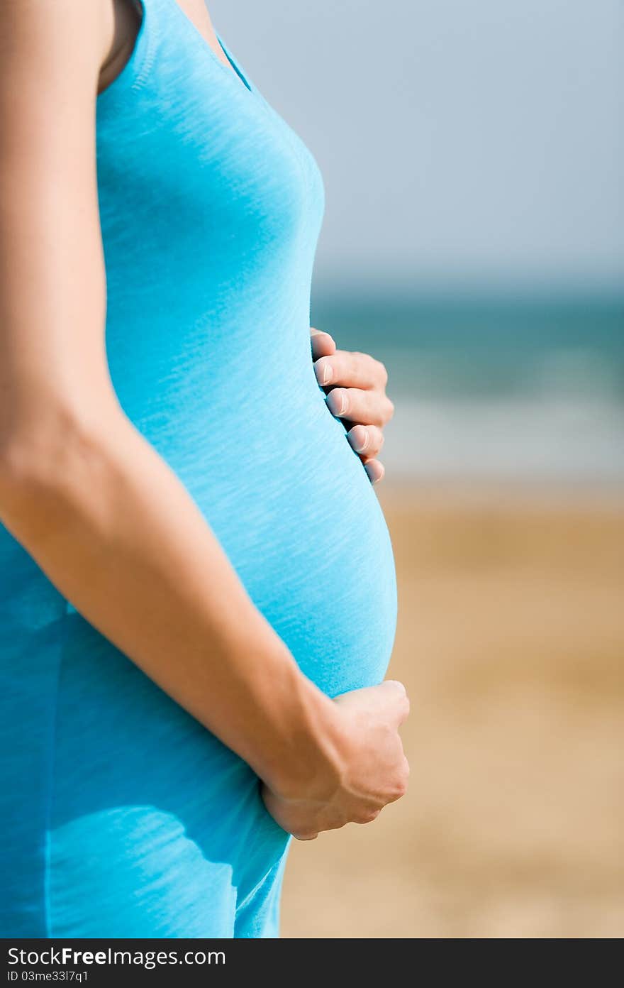 Woman in blue shirt is holding pregnant belly. Woman in blue shirt is holding pregnant belly