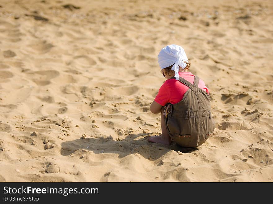 Little Child On The Beach Is Looking For Shells