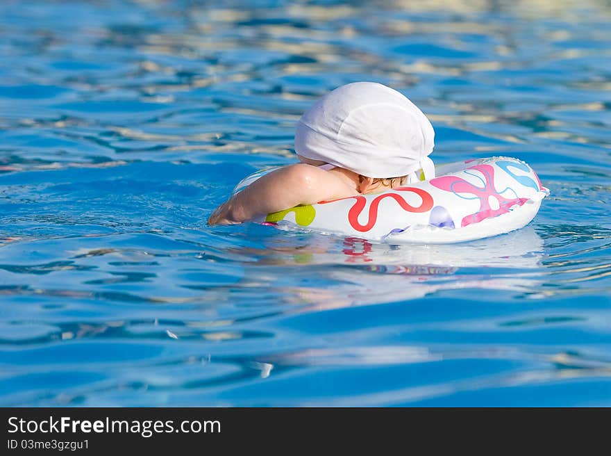 Baby in inflatable tube is swimming in pool