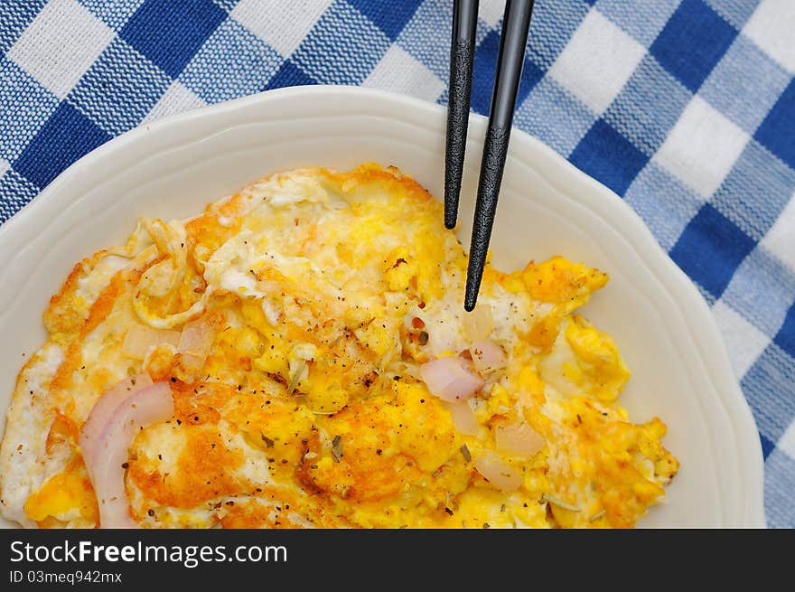 Onion fried egg on white plate with chopsticks.