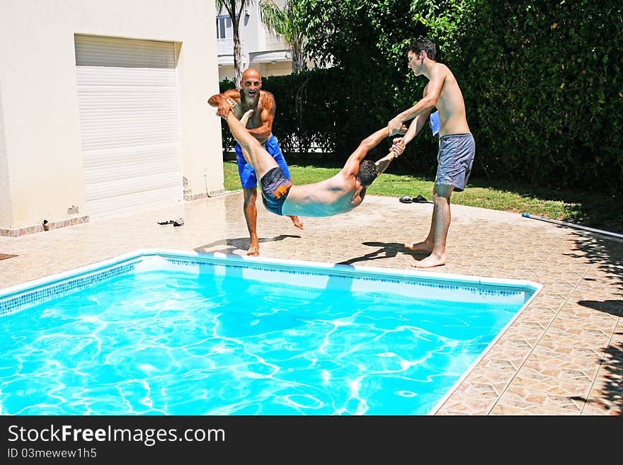 Men  throwing  their friend to swimming pool. Men  throwing  their friend to swimming pool.