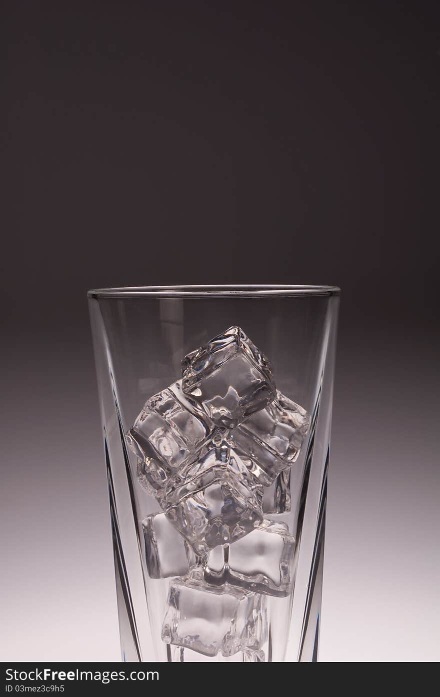 Clear glass with ice and soda with red straw shot against gradient background, glass dripping with droplets of water, seen from the top, cropped close.