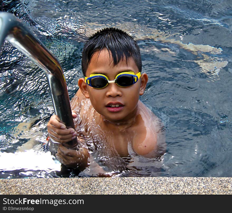 Asian boy wearing eye glass in swimming pool. Asian boy wearing eye glass in swimming pool