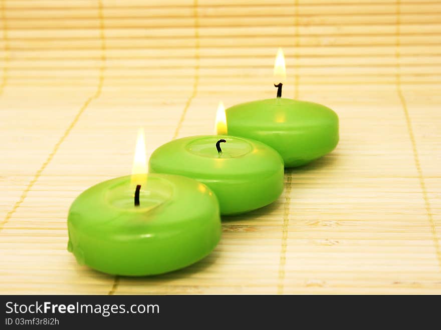 Green candles on bamboo background.