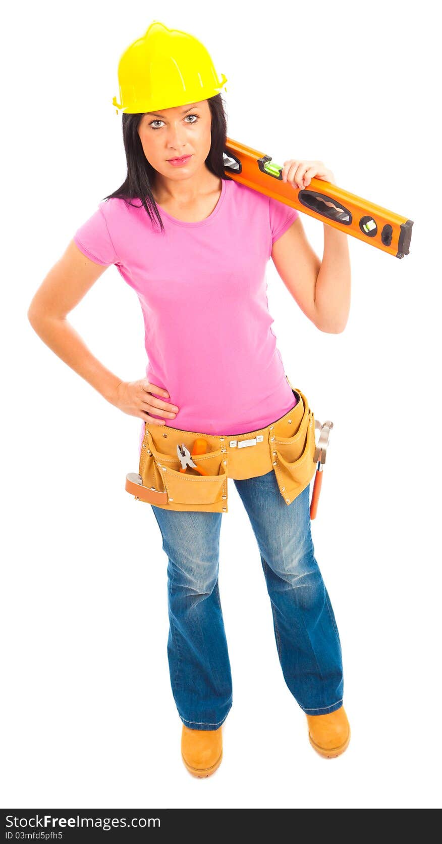 A young femamel dressed pin pink top and blue jeans wearing a tool belt holding a spirit level on isolated white background. A young femamel dressed pin pink top and blue jeans wearing a tool belt holding a spirit level on isolated white background