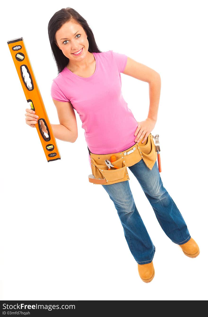 A young female dressed pin pink top and blue jeans wearing a tool belt holding a spirit level on isolated white background. A young female dressed pin pink top and blue jeans wearing a tool belt holding a spirit level on isolated white background