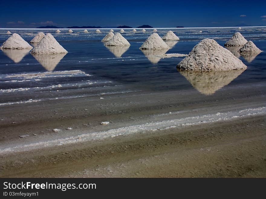 The endless flats of Salar de Uyuni, Bolivia. It was strange enough to see the lake covered in water as it was wet season, but the piles of salt extracted from the lake make it the most surreal place.