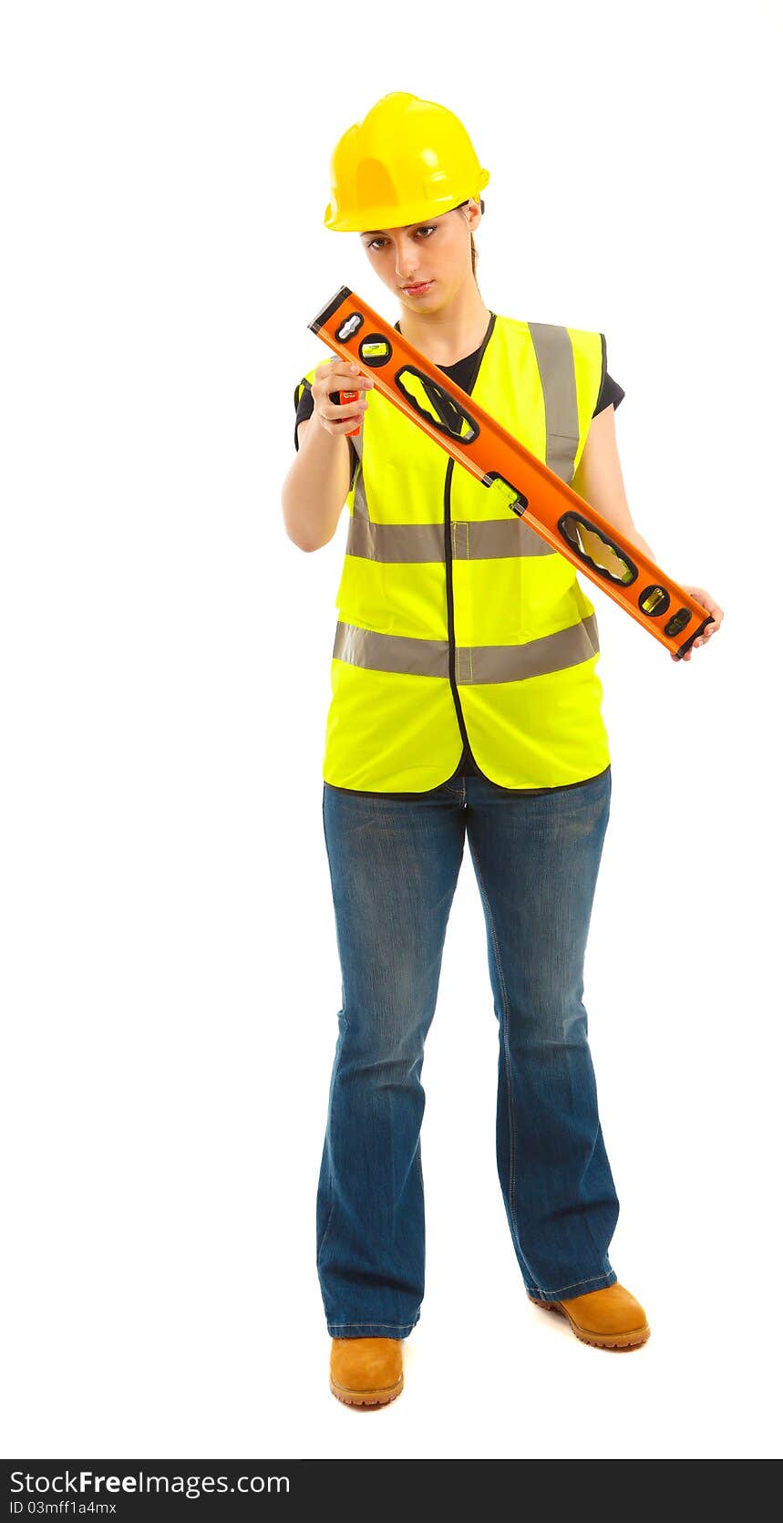 A female dressed in a high visibility vest looking a t a spirit level on isloated white background. A female dressed in a high visibility vest looking a t a spirit level on isloated white background