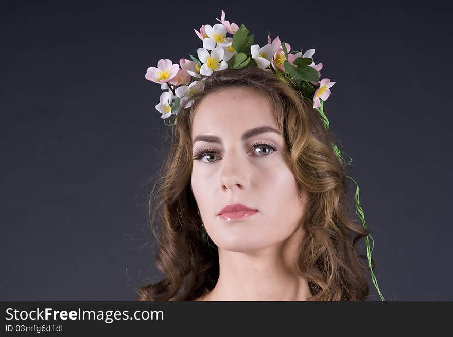 Portrait of a  beautiful girl with flowers in hair on a gray background closeup