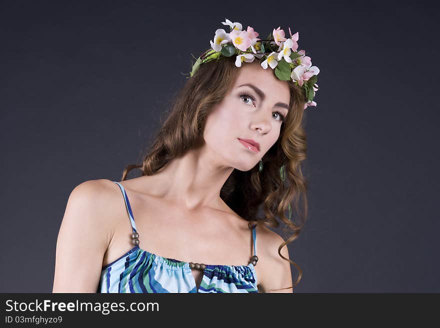 Portrait of a  beautiful girl with flowers in hair on a gray background closeup