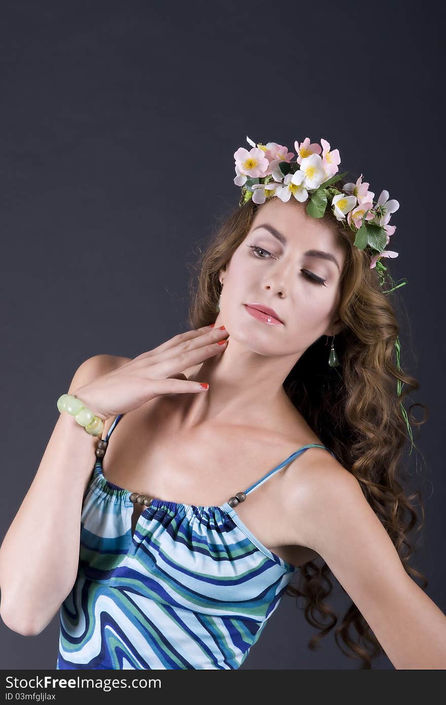 Portrait of a beautiful girl with flowers in hair on a gray background closeup