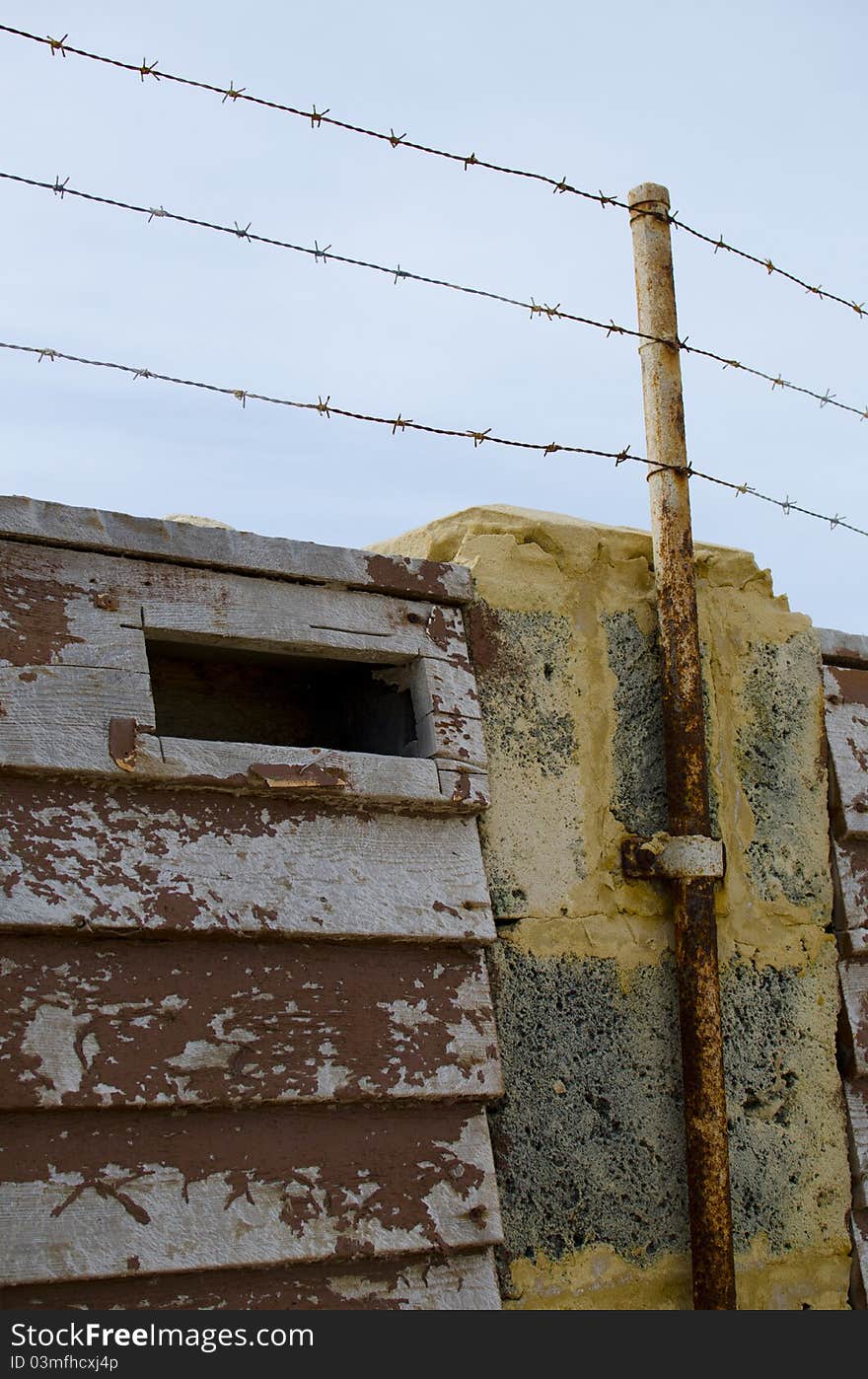 A barb wire security fence on top of a wall around a heavily secured property.