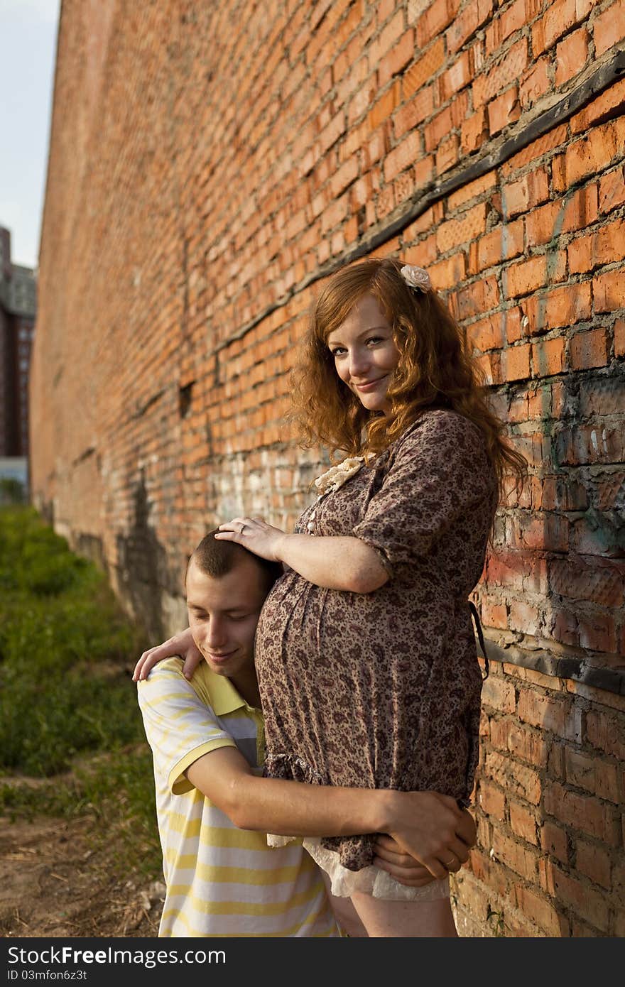 Portrait of a happy young man kisses his pregnant wife . outdoor .