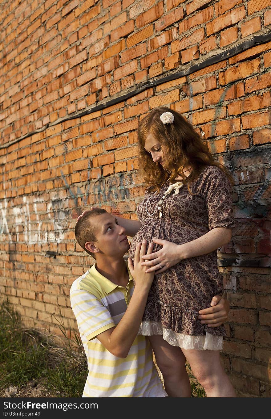 Portrait of a happy young man kisses his pregnant wife . outdoor .