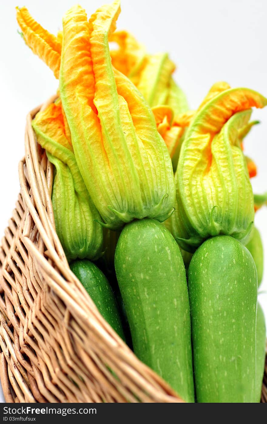 Zucchini with flowers in a basket on a white background. Zucchini with flowers in a basket on a white background