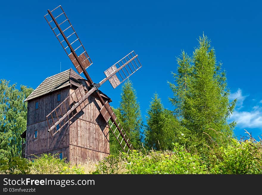 Old traditional wooden windmill hidden in forest.