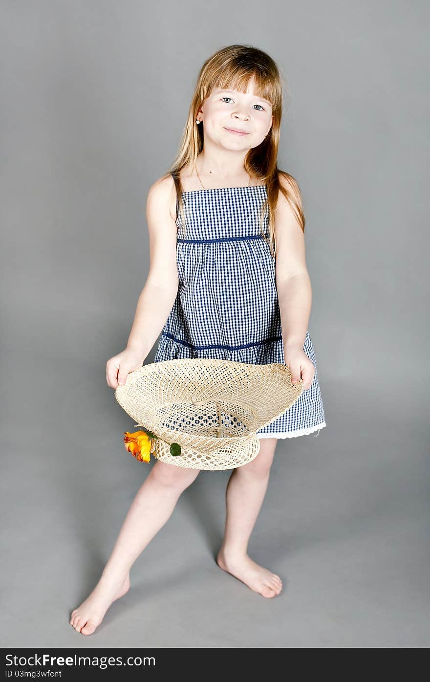 Little girl in a dress with a straw hat