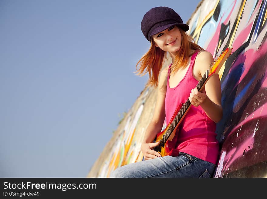 Girl with guitar and graffiti wall