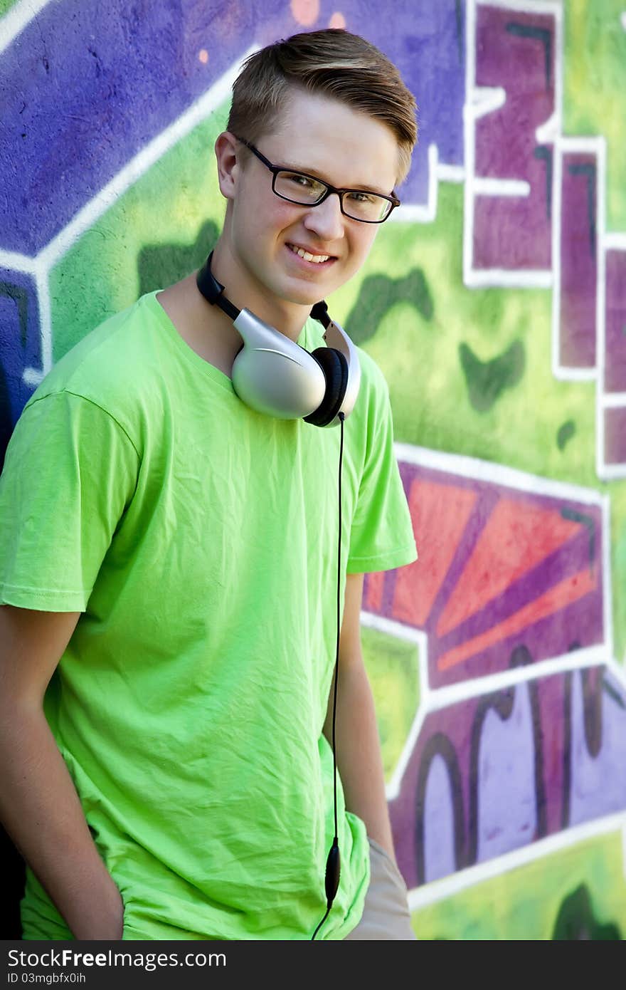 Teen Boy With Earphones Near Graffiti Wall.