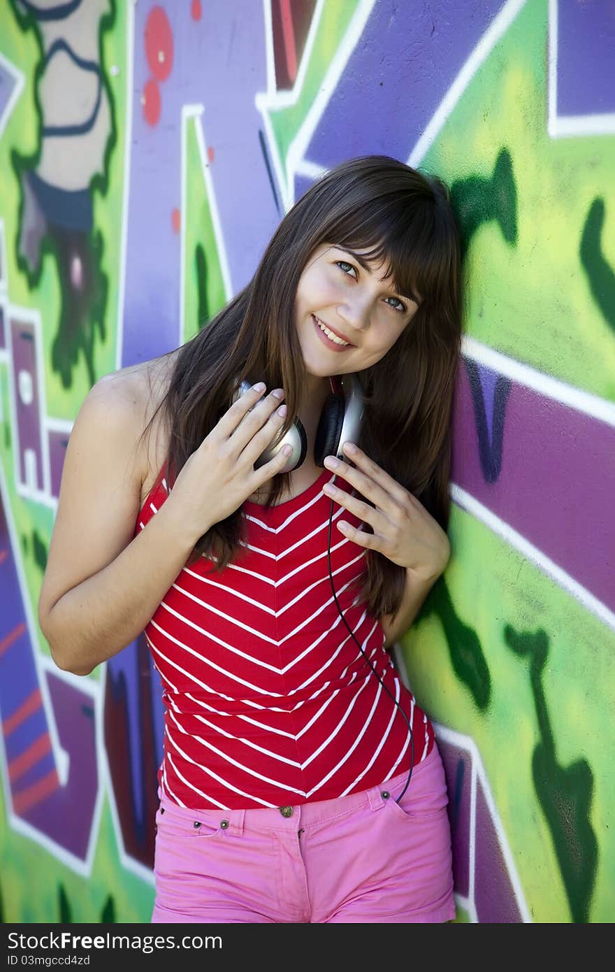 Girl with headphones and graffiti wall