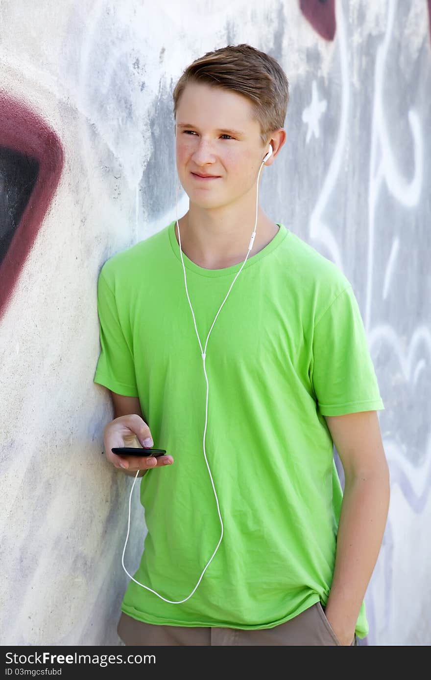 Teen Boy With Earphones Near Graffiti Wall.