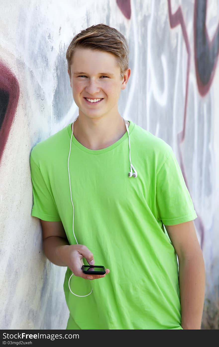 Teen Boy With Earphones Near Graffiti Wall.