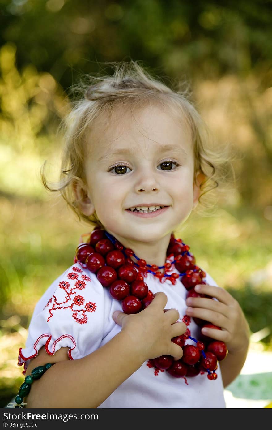 Little girl in traditional ukrainian costume on green grass at the park.