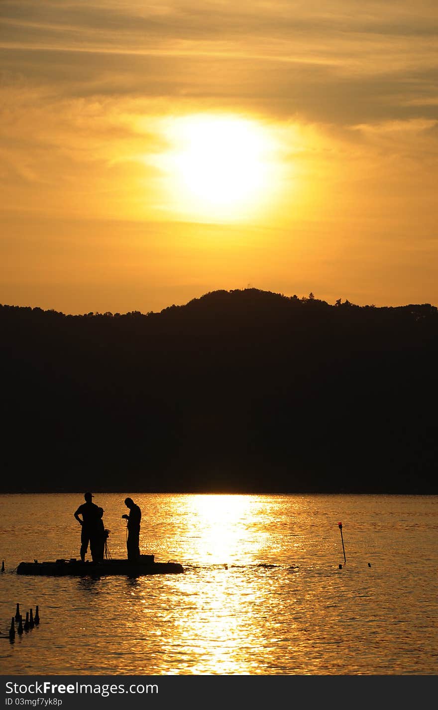 Three people preparing their bait before fishing on sunset. Three people preparing their bait before fishing on sunset