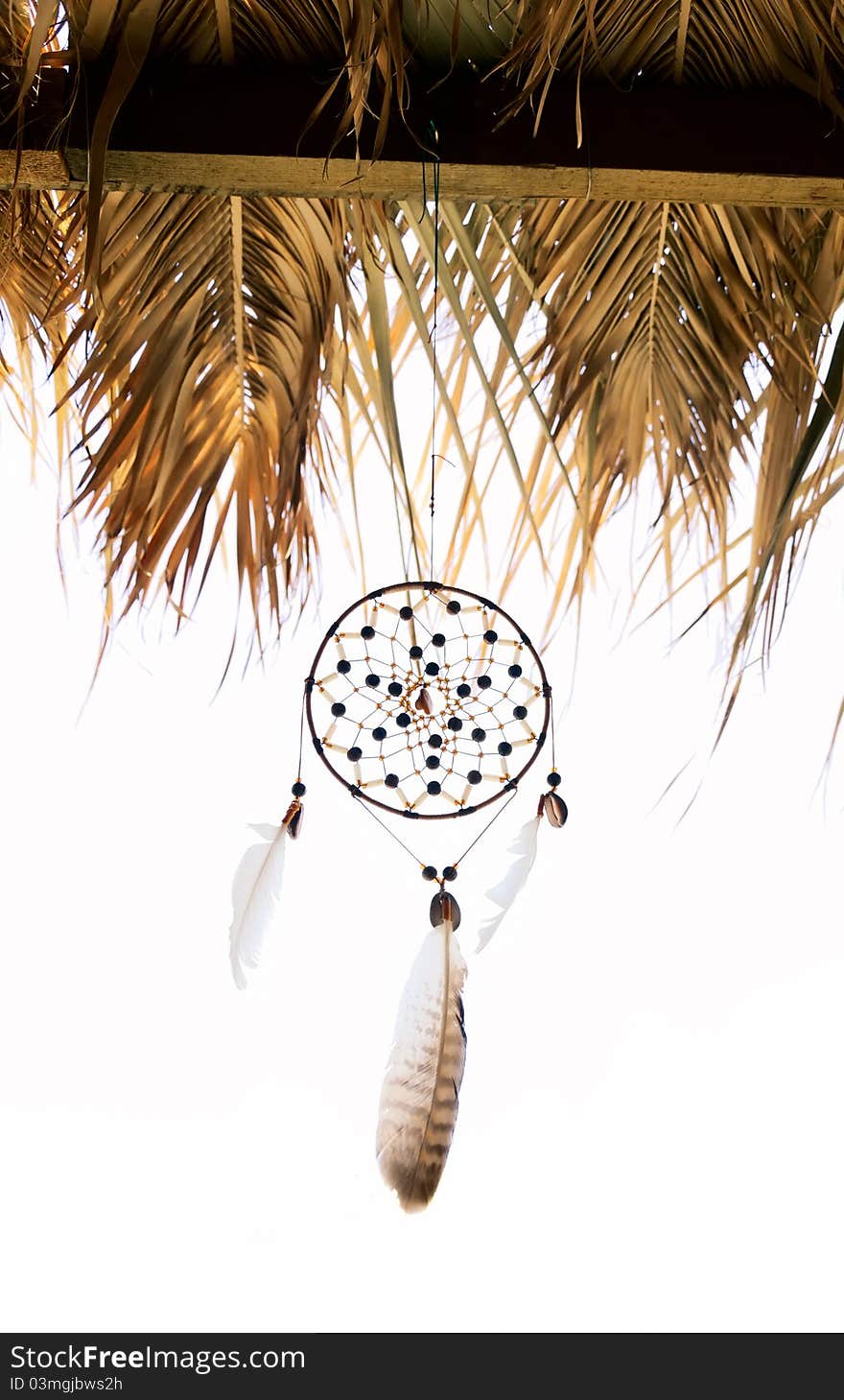 Dreamcatcher moved by wind under a roof on a white background