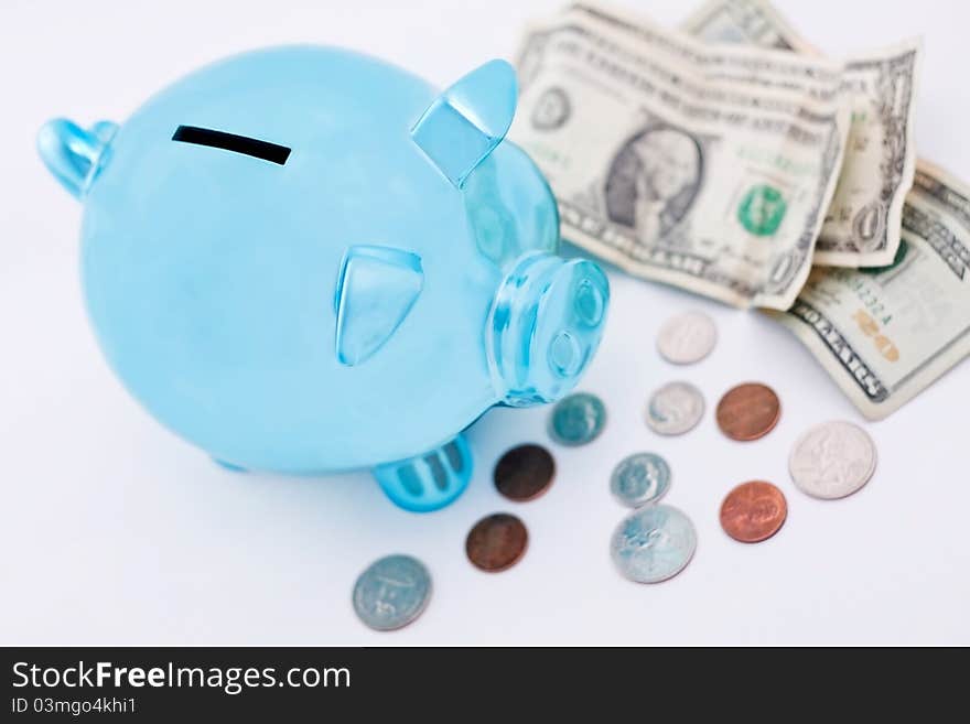 Metallic blue piggy bank and money ready to go inside it; selective focus on the bank. Metallic blue piggy bank and money ready to go inside it; selective focus on the bank