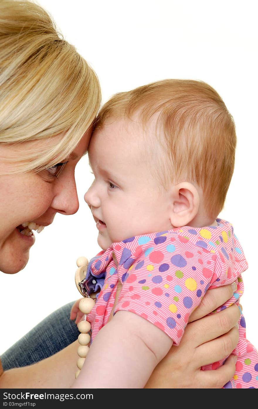 Mother is looking down on her sweet smiling baby. Taken on a white background. Mother is looking down on her sweet smiling baby. Taken on a white background.