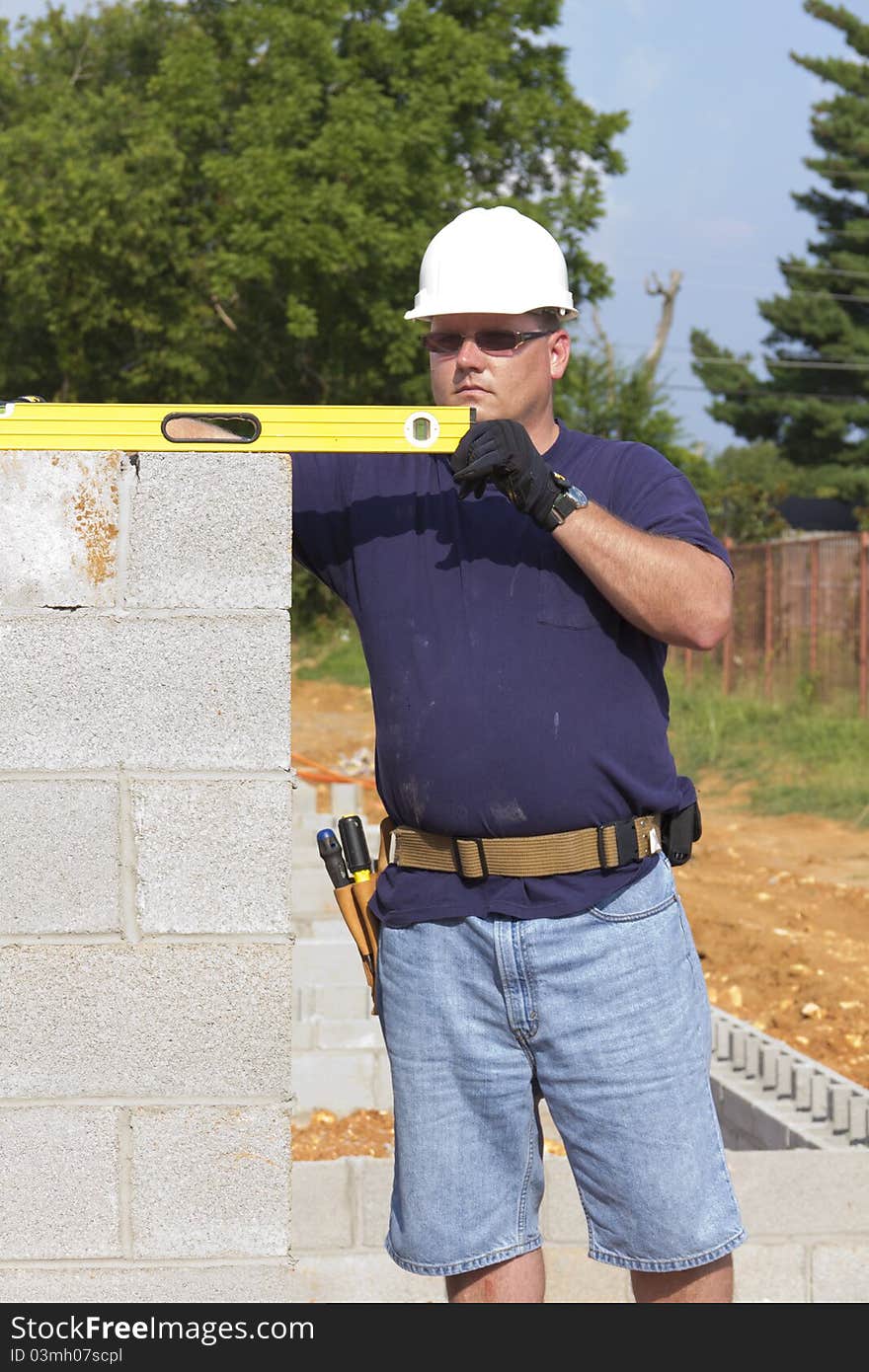 Supervisor checking cinder block where masons are building walls. Supervisor checking cinder block where masons are building walls