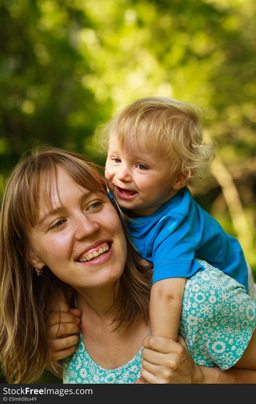 Mother with her son piggy-back in the summer forest, enjoying playing together. Mother with her son piggy-back in the summer forest, enjoying playing together