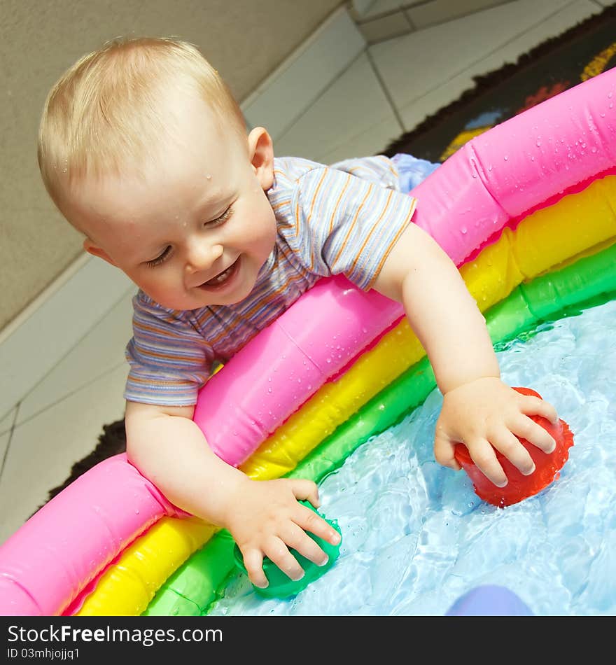 Baby boy at plastic pool playing with toys and water. Baby boy at plastic pool playing with toys and water.