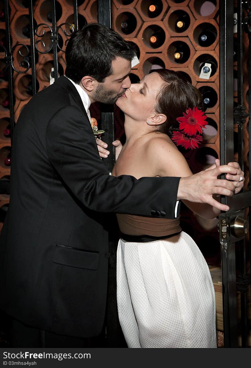 A bride and groom share a kiss in a wine cellar after their wedding. A bride and groom share a kiss in a wine cellar after their wedding.