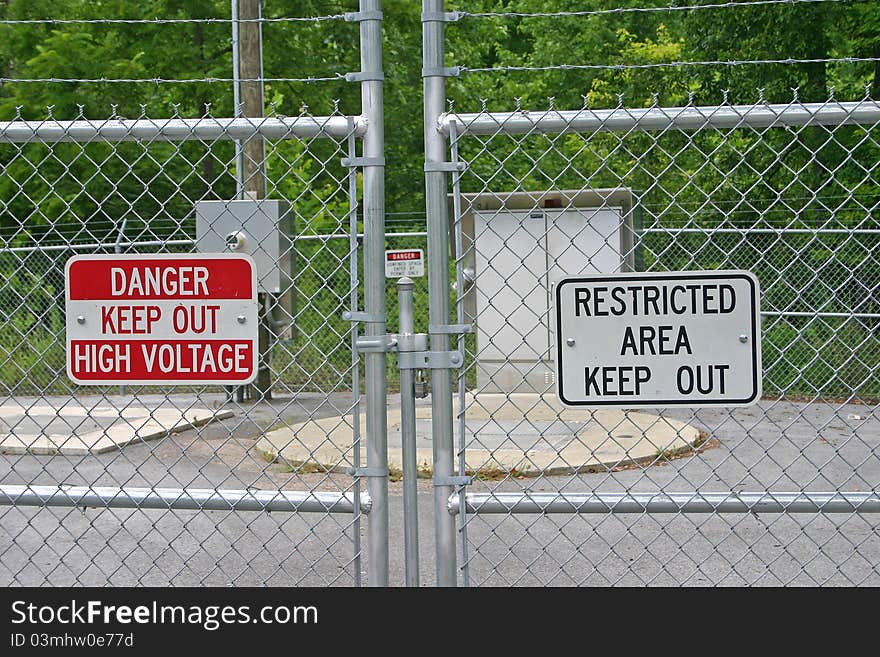 A chain link fence and warning signs barring access to a restricted area. A chain link fence and warning signs barring access to a restricted area