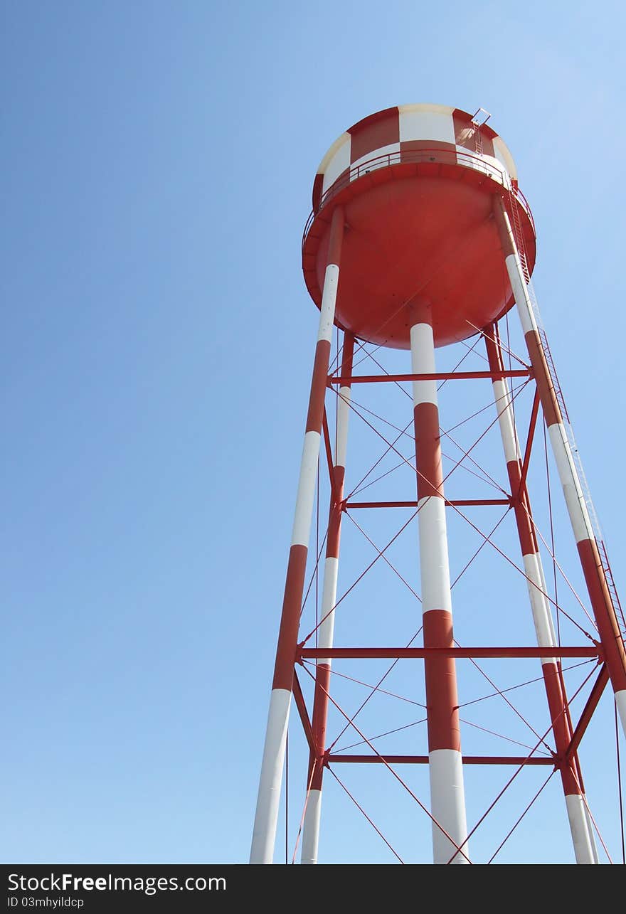 A red and white water tower reaches toward the sky. A red and white water tower reaches toward the sky