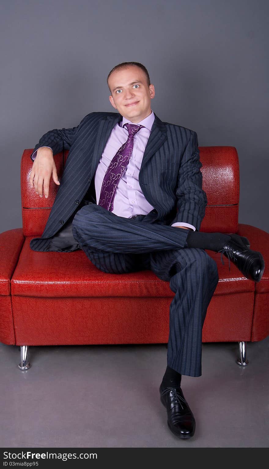 Thoughtful guy in a suit sitting on a red couch