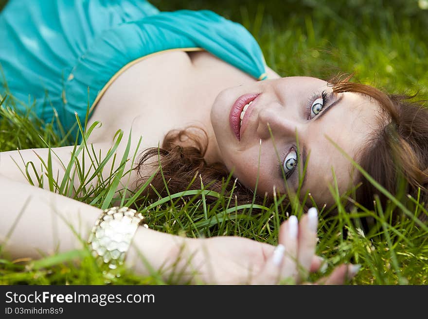 Beautiful brunette girl in a blue dress lying on a rock