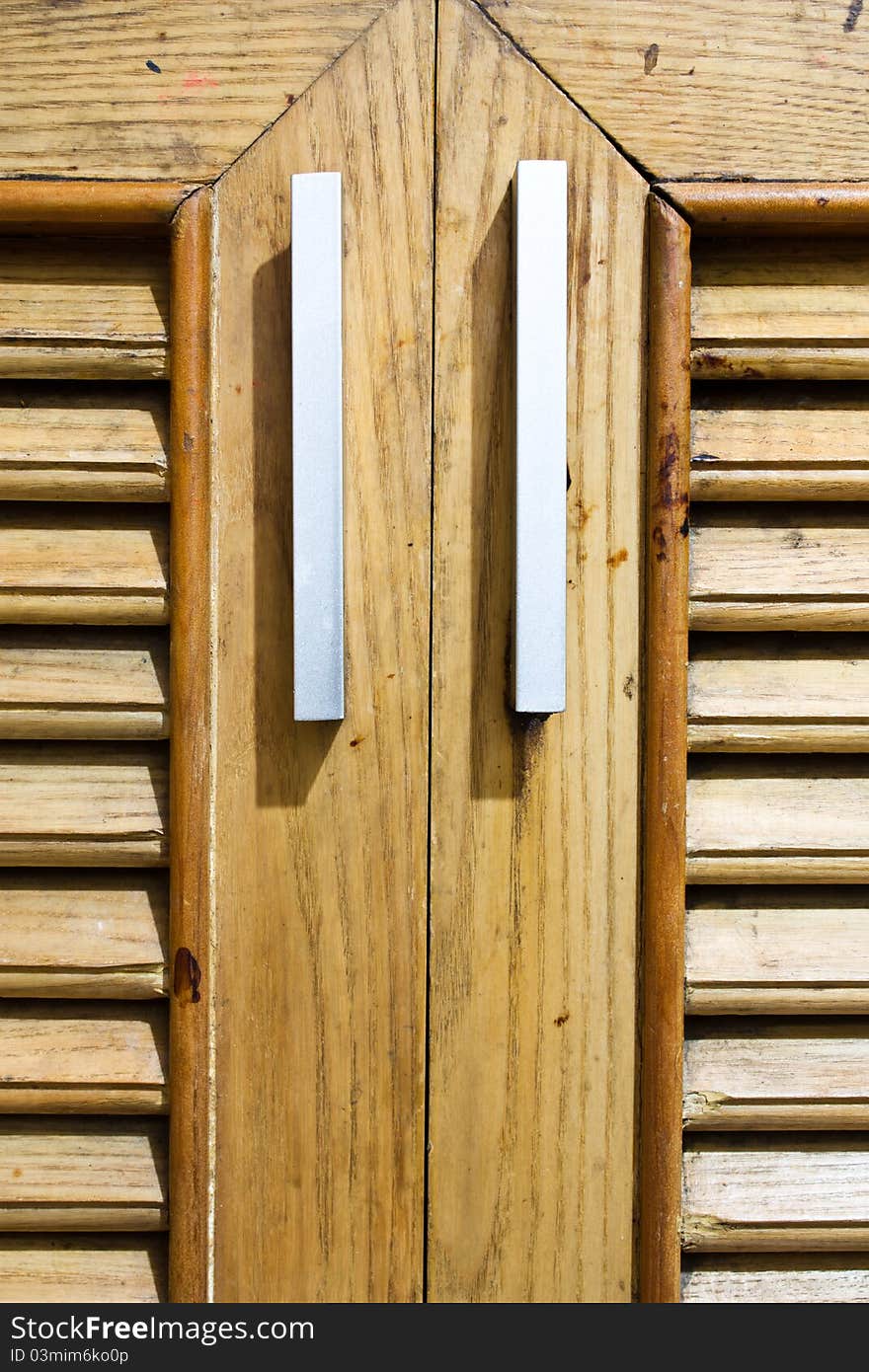 A wooden door with a handle of the cabinet. A wooden door with a handle of the cabinet