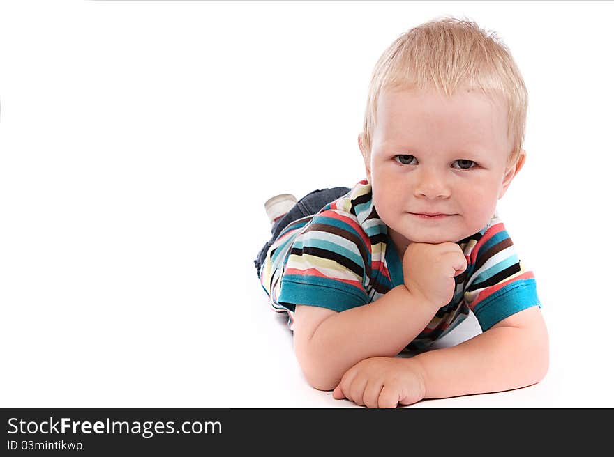 Portrait of a happy 2 year boy lying on a floor.