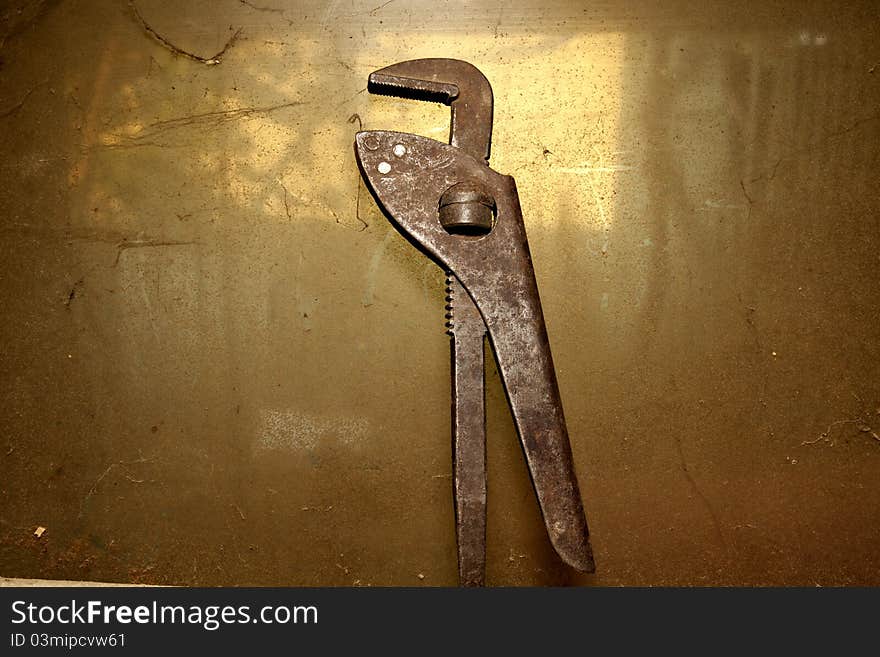 Old pipe wrench isolated on dirty background